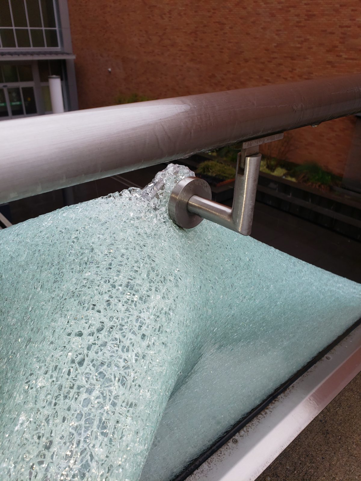 Damaged glass railing panel before replacement